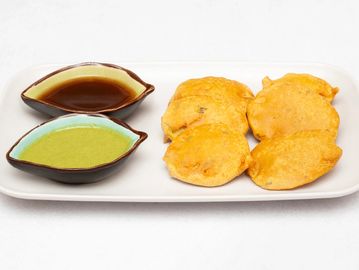 Plate of golden fried snacks with two dipping sauces on a white platter.