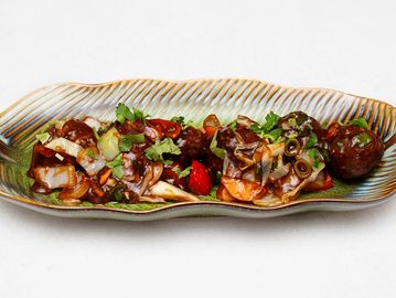 Szechuan-style spicy meatballs with vegetables on a decorative plate.