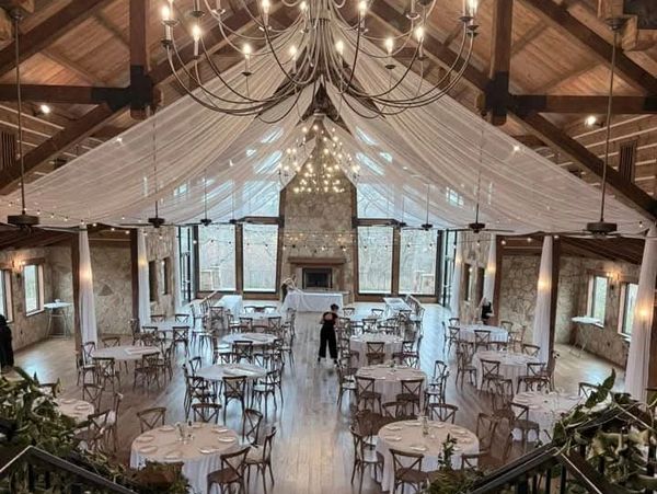 Elegant rustic event hall with round tables and soft lighting.