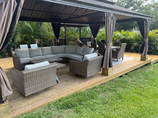 Outdoor gazebo with cushioned seating and dining area on wooden deck.
