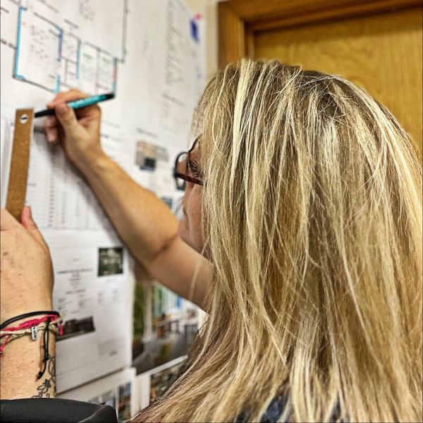 Logipops owner, Christine Hedding measuring blueprints for an interior branding project.