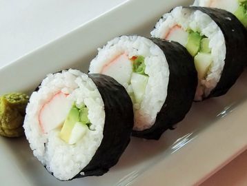 Close-up of sushi rolls with wasabi on a plate.