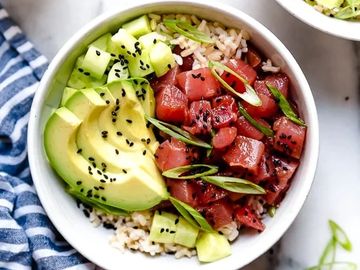 Poke bowl with tuna, avocado, cucumber, rice, and black sesame seeds.