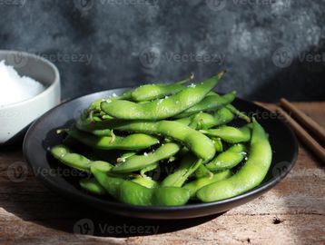 Fresh edamame with sea salt in a black bowl.