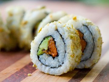 Close-up of sushi rolls on wooden board.