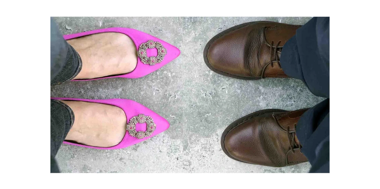 A person wearing pink ladies' shoes faces  a person wearing brown men's shoes