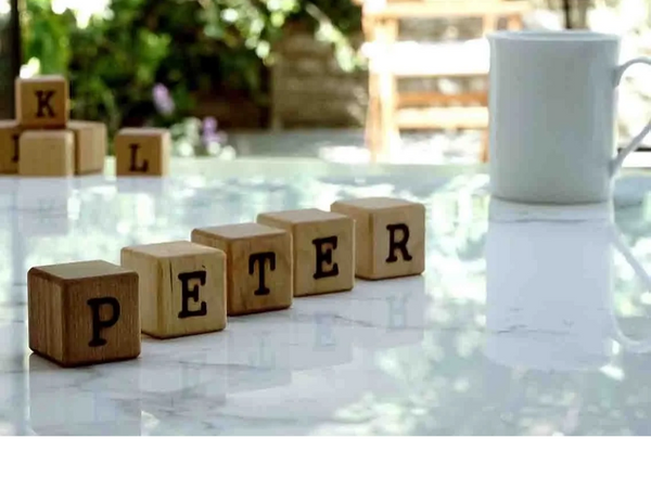 Small blocks spell out the name PETER on a marble top with garden view behind