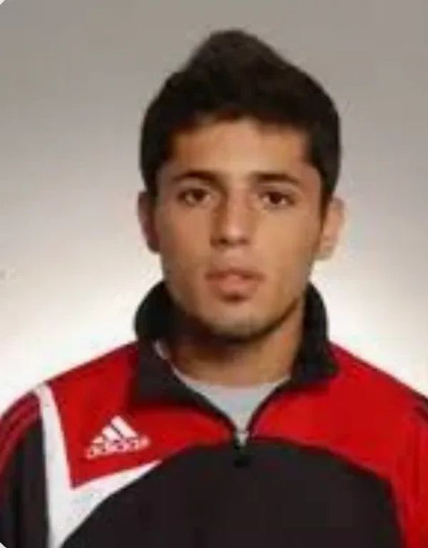 Portrait of a young man in a red and black Adidas sports jacket.