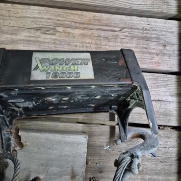 A Power Winch 10000 with rust on metal parts on wooden floor.