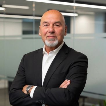 Confident businessman in a black suit with arms crossed.