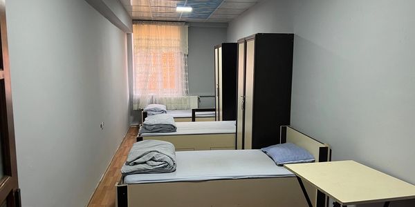 A simple dorm room with three single beds and wardrobes.