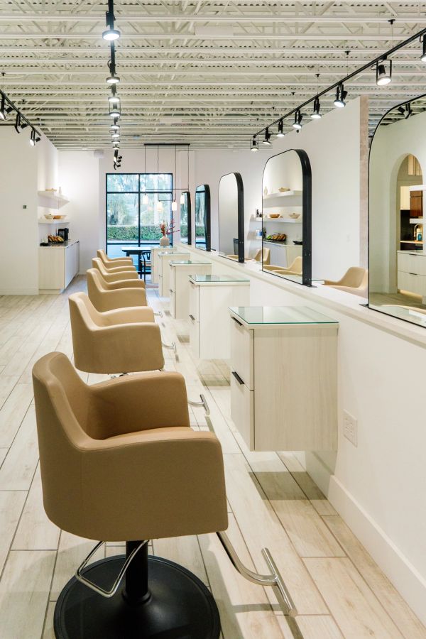 Modern salon with beige chairs and mirrors.