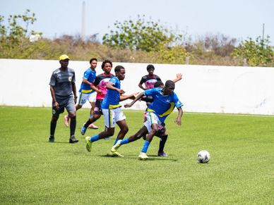 Soccer players competing intensely on a sunny field.