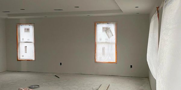 An unfinished room under construction with covered windows and scattered materials.