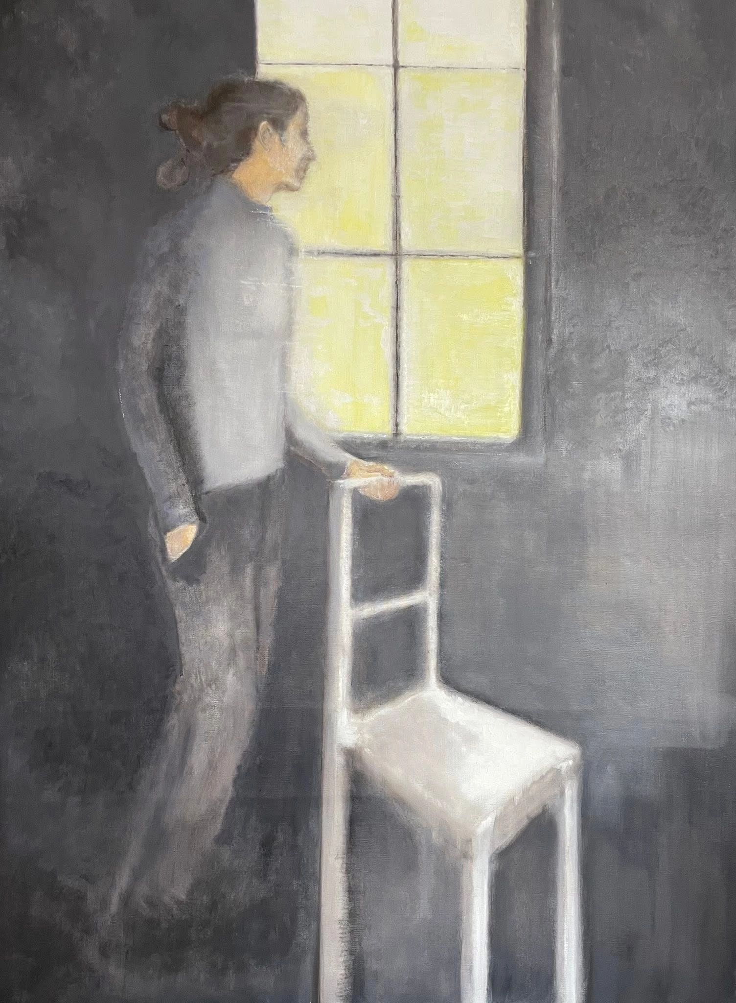 Personne à côté d'une chaise près d'une fenêtre lumineuse.