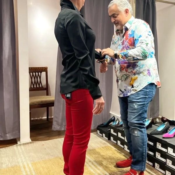 Personal stylist is dressing a client in red velvet jeans and black button up blouse.