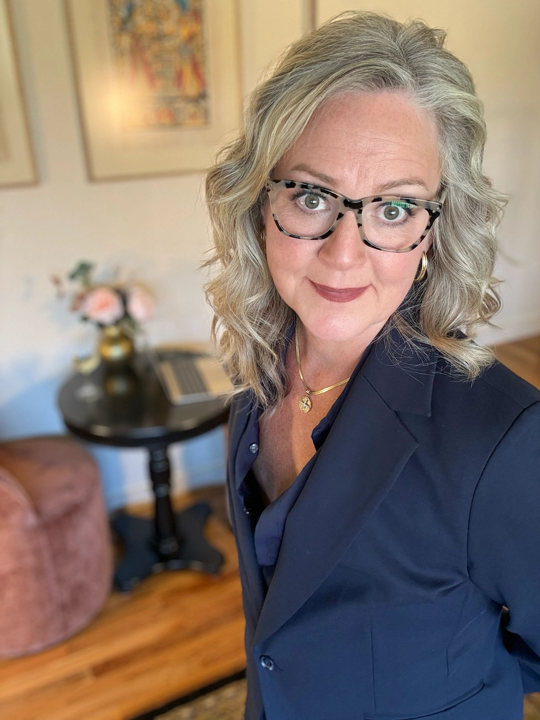 Confident woman with glasses and wavy hair.