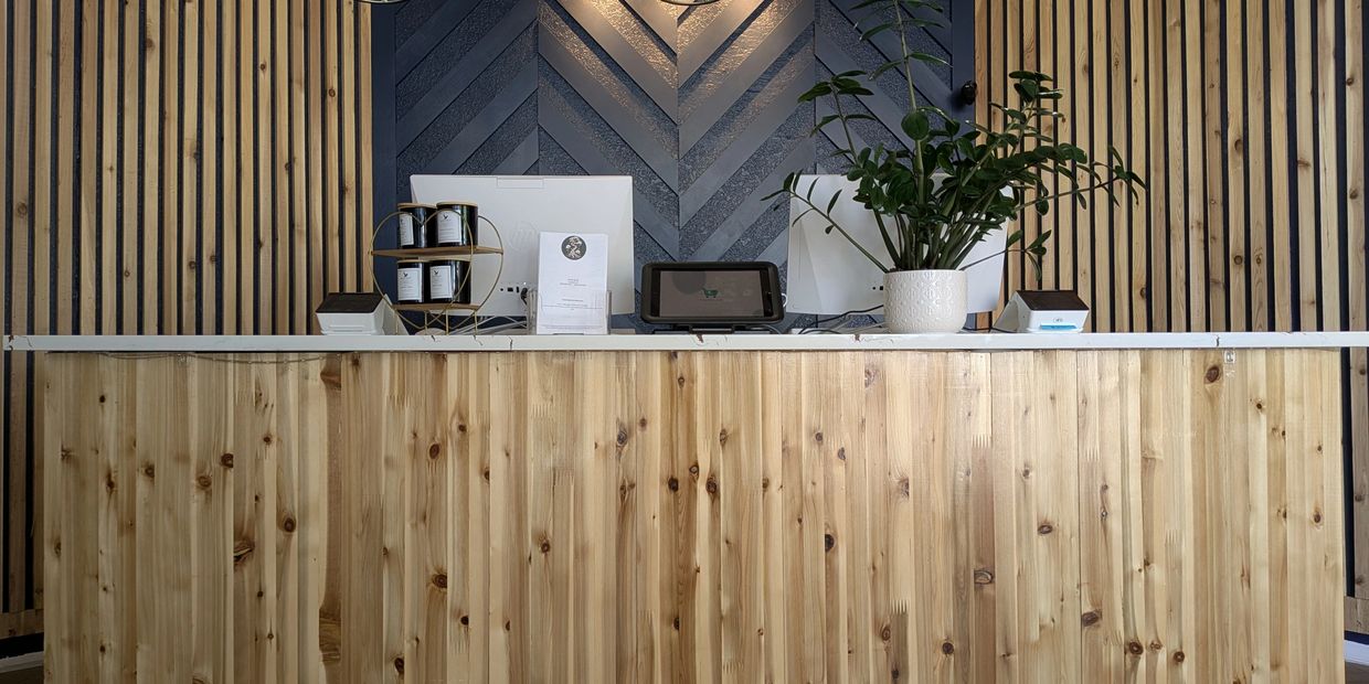 Modern wooden reception desk with accent wall and hanging lights. Loveland, CO