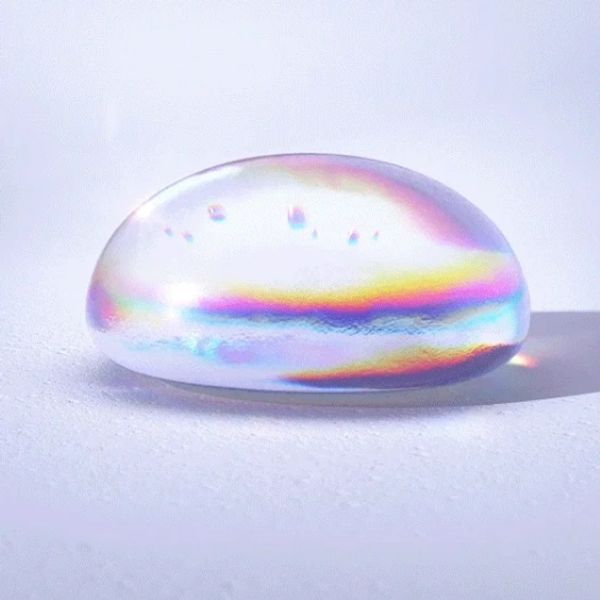 A translucent, iridescent hyaluronic acid droplet on a smooth surface.