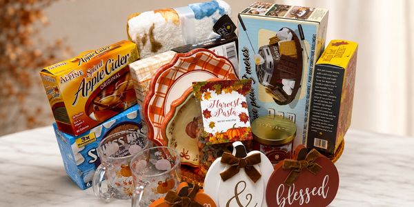 Canasta de regalo otoñal con productos y decoraciones temáticas.