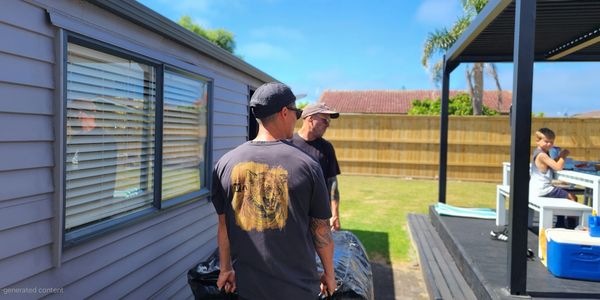 Two men working outdoors while a child sits at a table under a pergola.