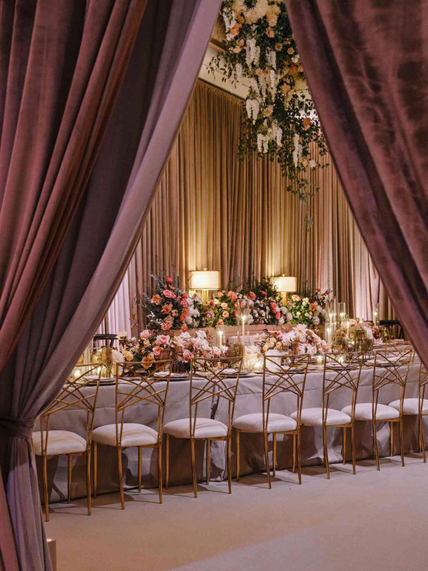 Elegant dining setup with gold chairs, floral arrangements, and soft lighting.