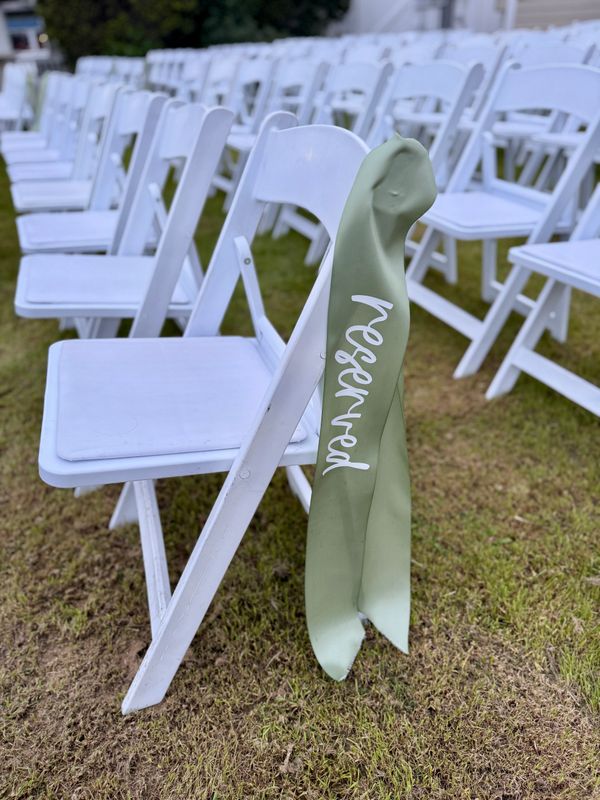 Rows of white chairs with a reserved sign on one chair.