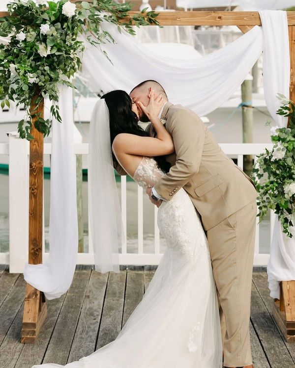 Bride and groom sharing a kiss under a floral wedding arch.