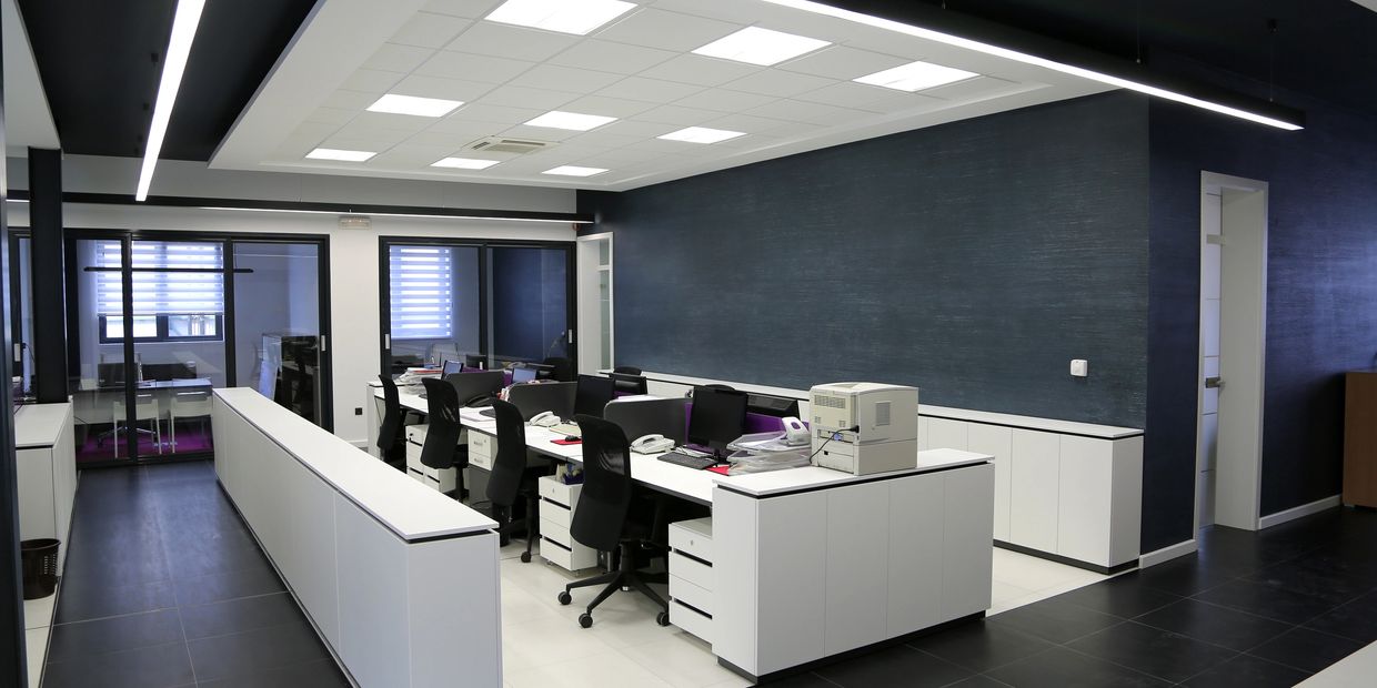Modern office space with black and white decor and multiple workstations.