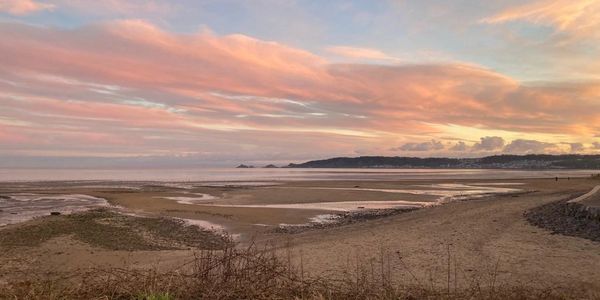 Swansea bay at just before sunset with the clouds turning pink