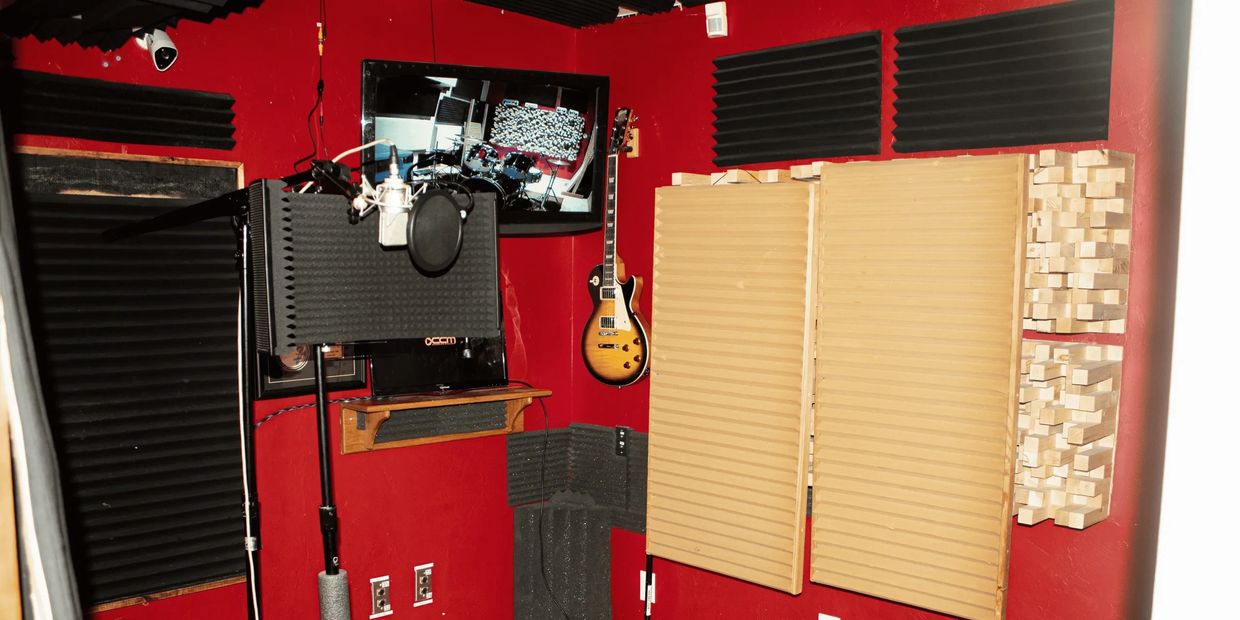 A recording studio with red walls, a microphone, and a guitar.