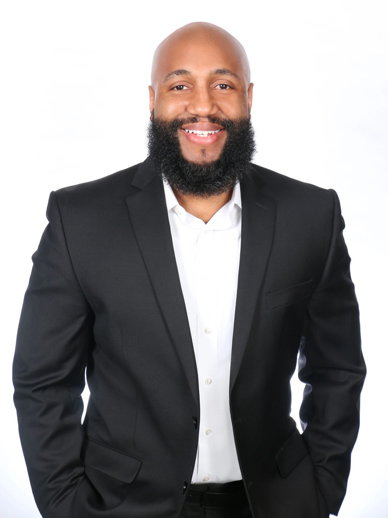 Smiling man in black suit and white shirt.