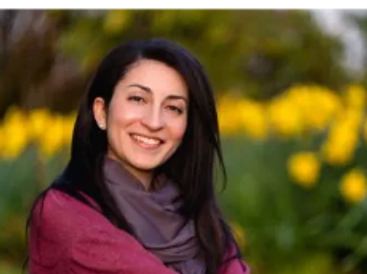 Smiling woman outdoors with yellow flowers in the background.