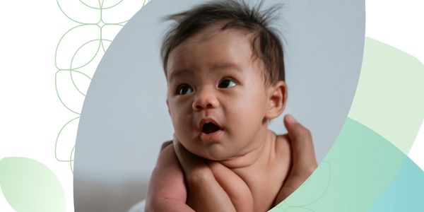 Close-up of a curious baby being held gently.