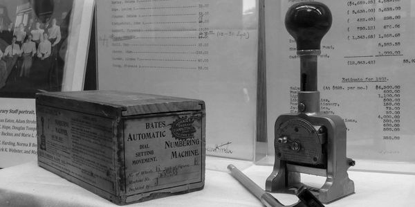 Vintage Bates Automatic Numbering Machine with its original wooden box and a pencil on display.