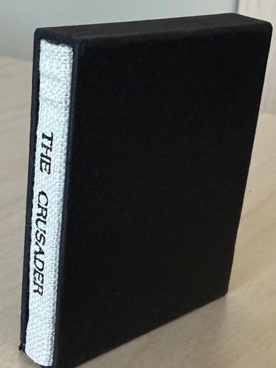 A small black book with a white spine titled 'THE CRUSADER'.