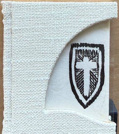 Book with textured white cover and black cross emblem on inner page.