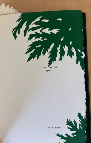 Intricate green leaf cutouts frame a dedication page in a book.