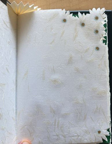 Decorative handmade paper with floral cutouts and textured fibers.