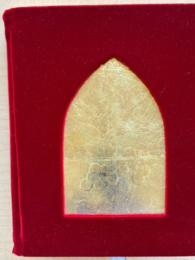 Red velvet book cover with a gold, arched window design.