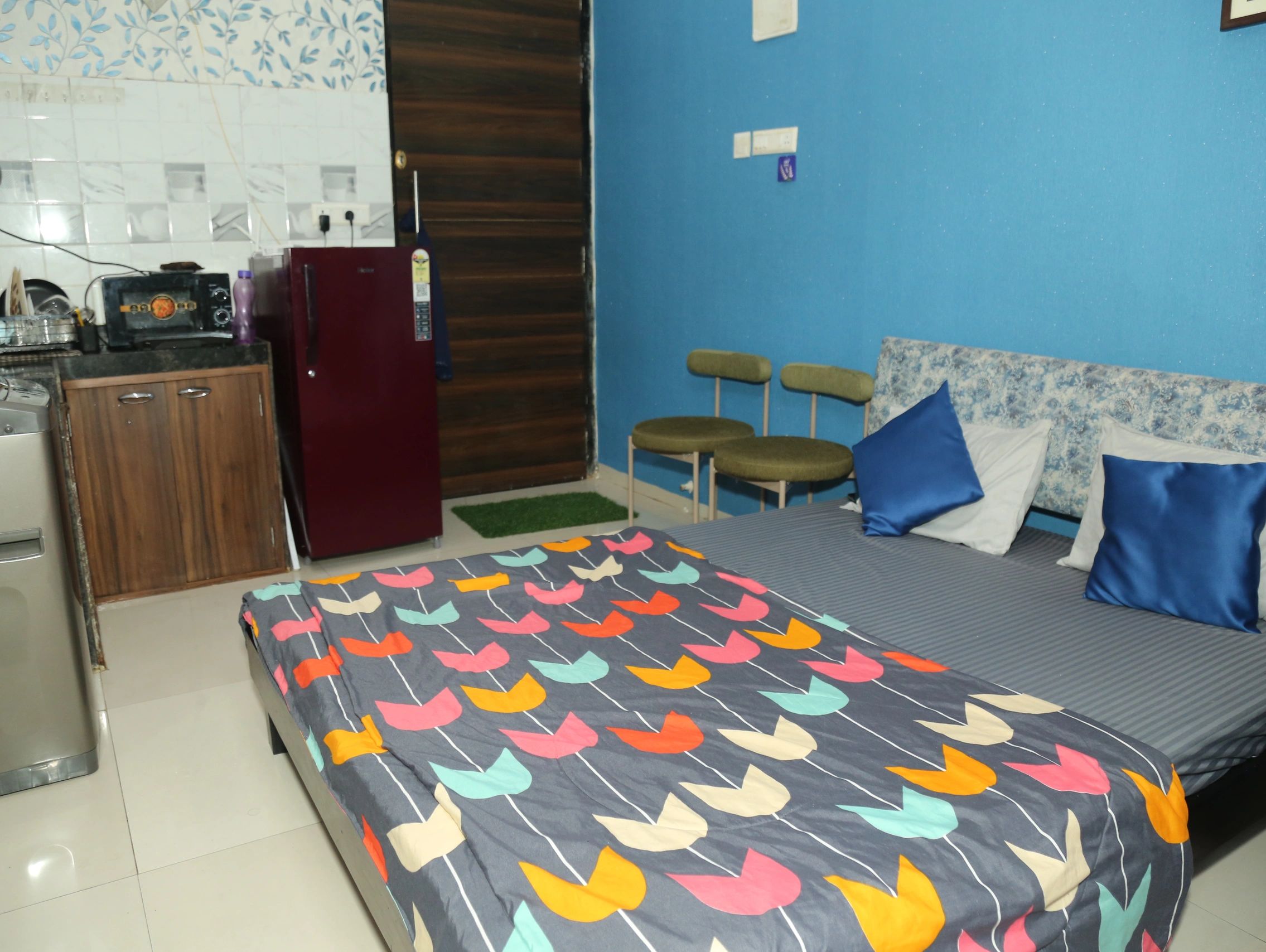 Cozy bedroom with a colorful bedspread and blue walls.