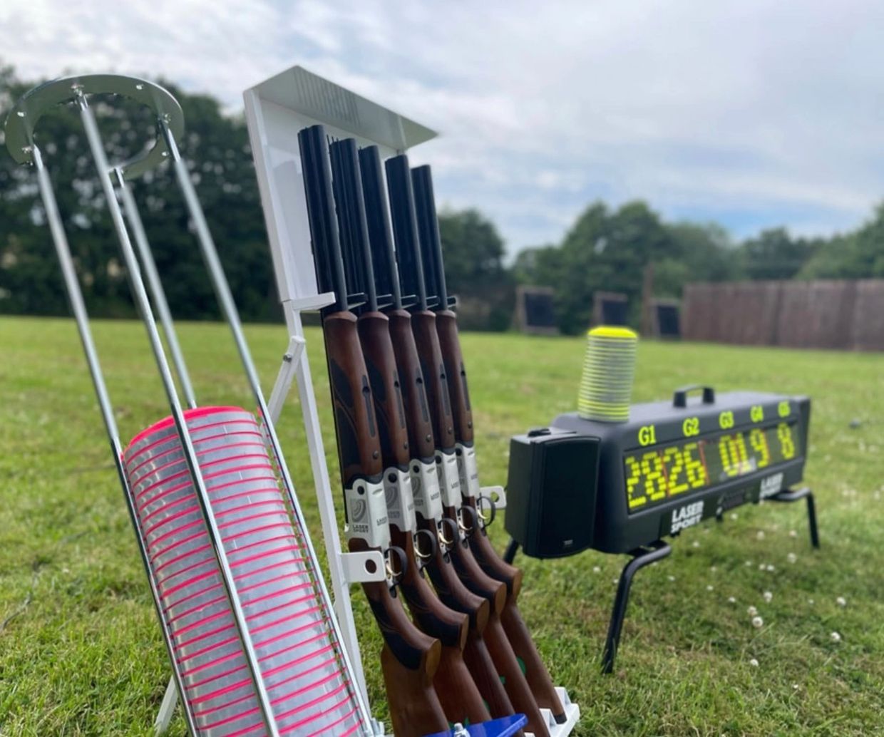 Trap shooting guns, traps, and an electronic scoreboard outdoors.