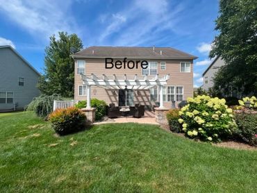 Backyard of a house before renovation with patio and greenery.