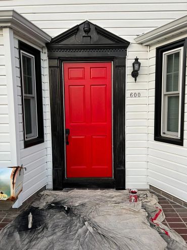 Bright red door with black trim on a white house.
