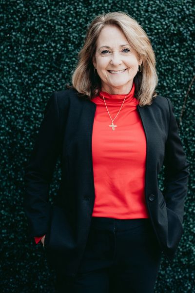 Smiling woman in a red top and black blazer.