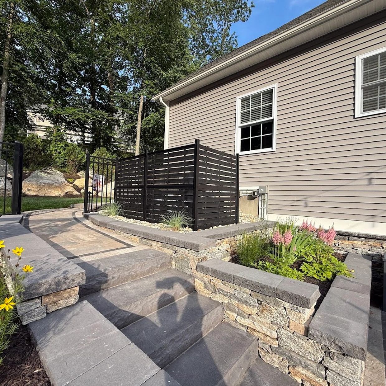 Modern stone patio with raised garden beds and stairs.