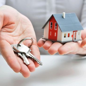 Two hands holding a miniature house and a set of keys