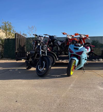 Two motorcycles parked in front of a trailer carrying dirt bikes.