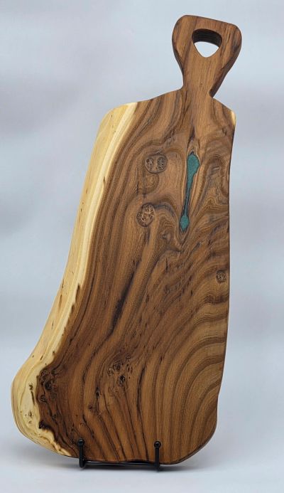 Handcrafted wooden cutting board with natural grain and a handle.
