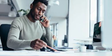 Man working at desk while talking on phone.
